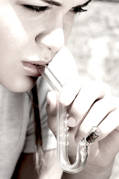 Girl smoking through glass pipe.